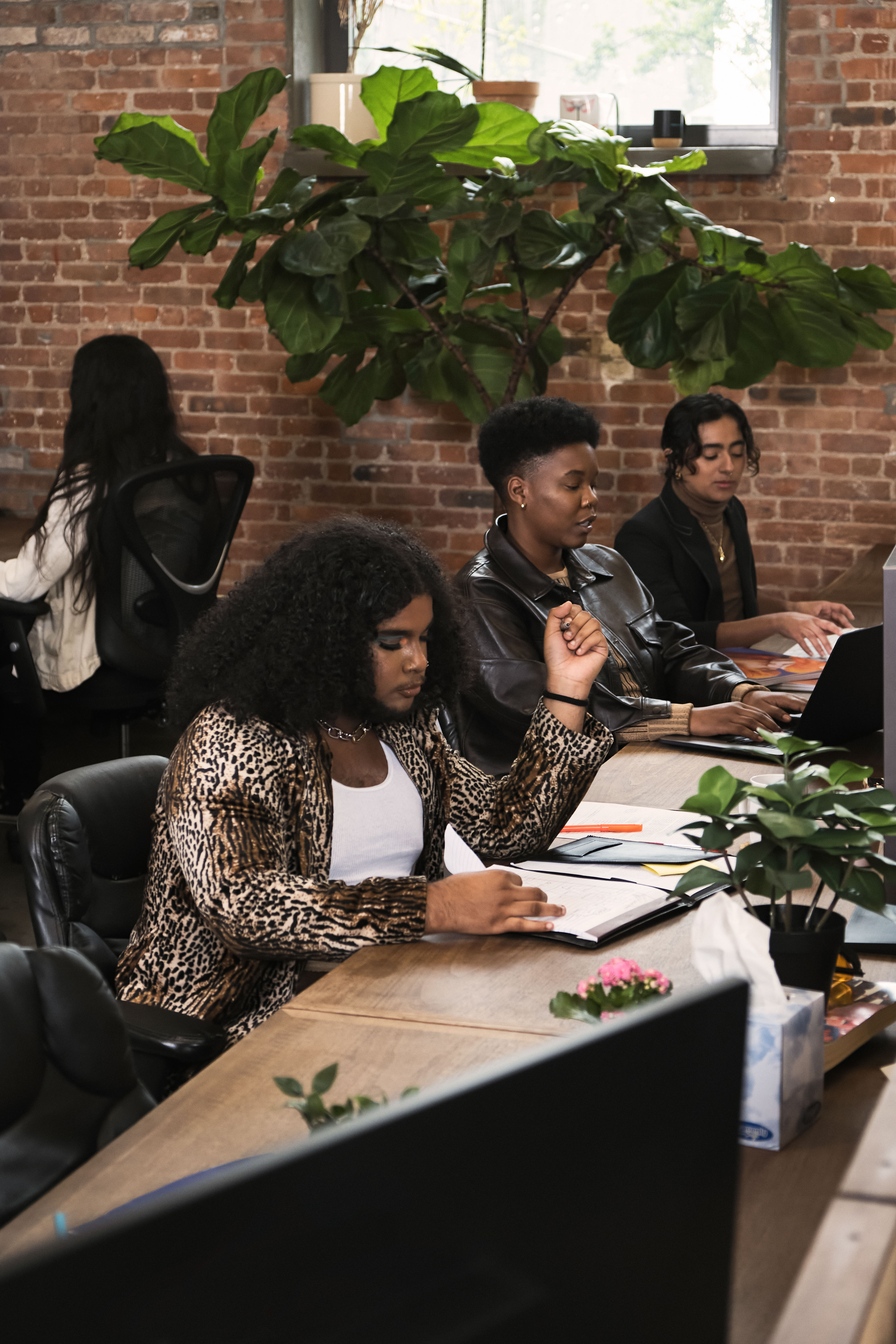 A group of people of varying genders work in an office(1)